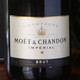 A close-up of a bottle of Moët & Chandon Champagne, featuring a label that reads "Champagne Moët & Chandon Impérial Brut." The bottle is predominantly dark with gold and white accents, displaying details such as the volume percentage of 12% and the origin "Epernay, France." A close-up of a bottle of Moët & Chandon Champagne, featuring a label that reads "Champagne Moët & Chandon Impérial Brut." The bottle is predominantly dark with gold and white accents, displaying details such as the volume percentage of 12% and the origin "Epernay, France."